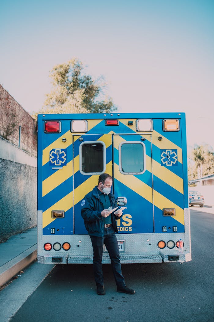 services-01 A paramedic prepares for duty next to a parked ambulance on a city street.