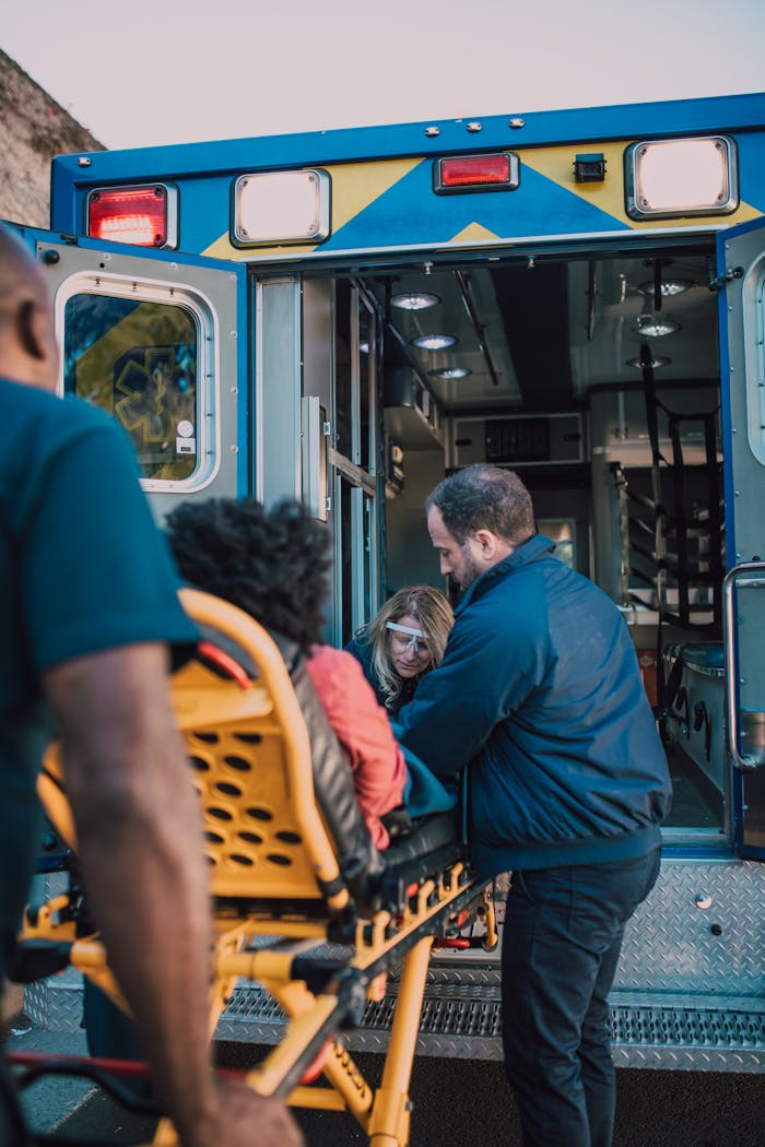journey Paramedics help a patient on a stretcher into an ambulance for medical assistance.