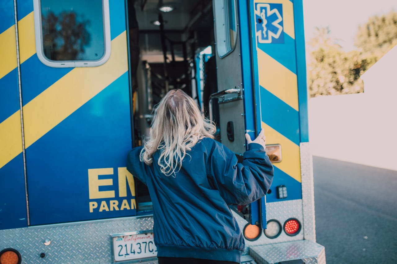 services-02 A woman in a navy jacket boarding an ambulance, showcasing emergency services in action.