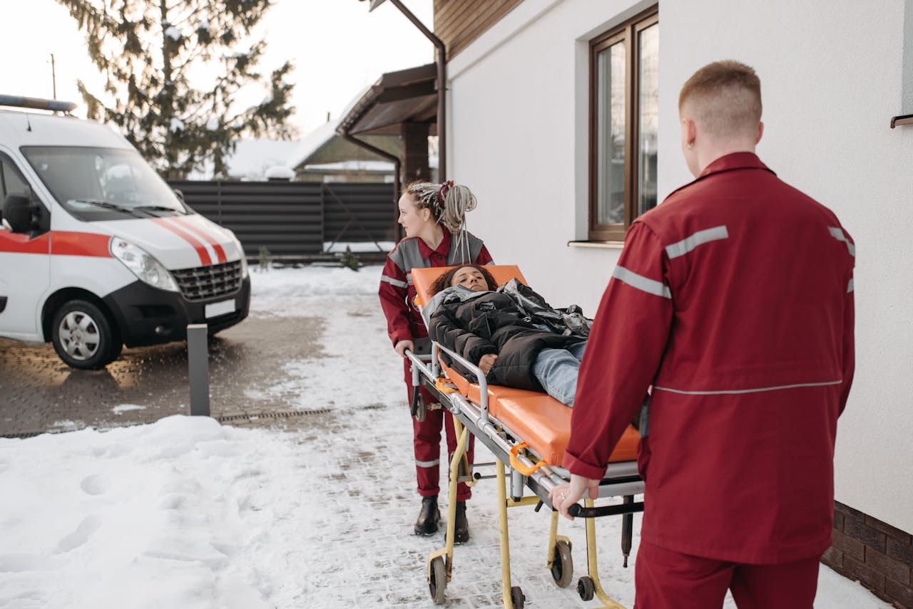 Emergency responders transport a patient on a stretcher outside in snowy conditions.