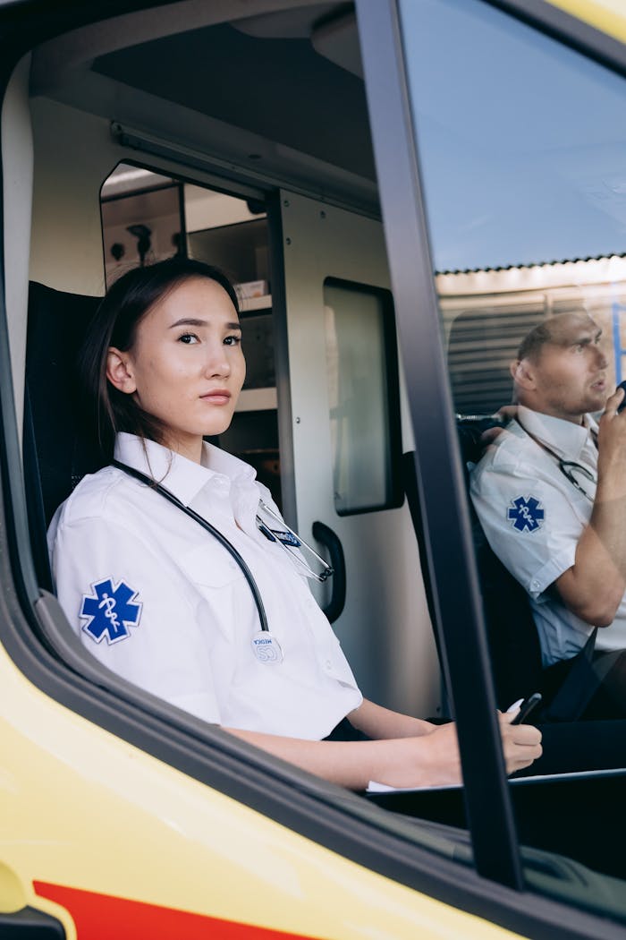 Paramedics in uniform seated inside an ambulance, prepared for emergency response.